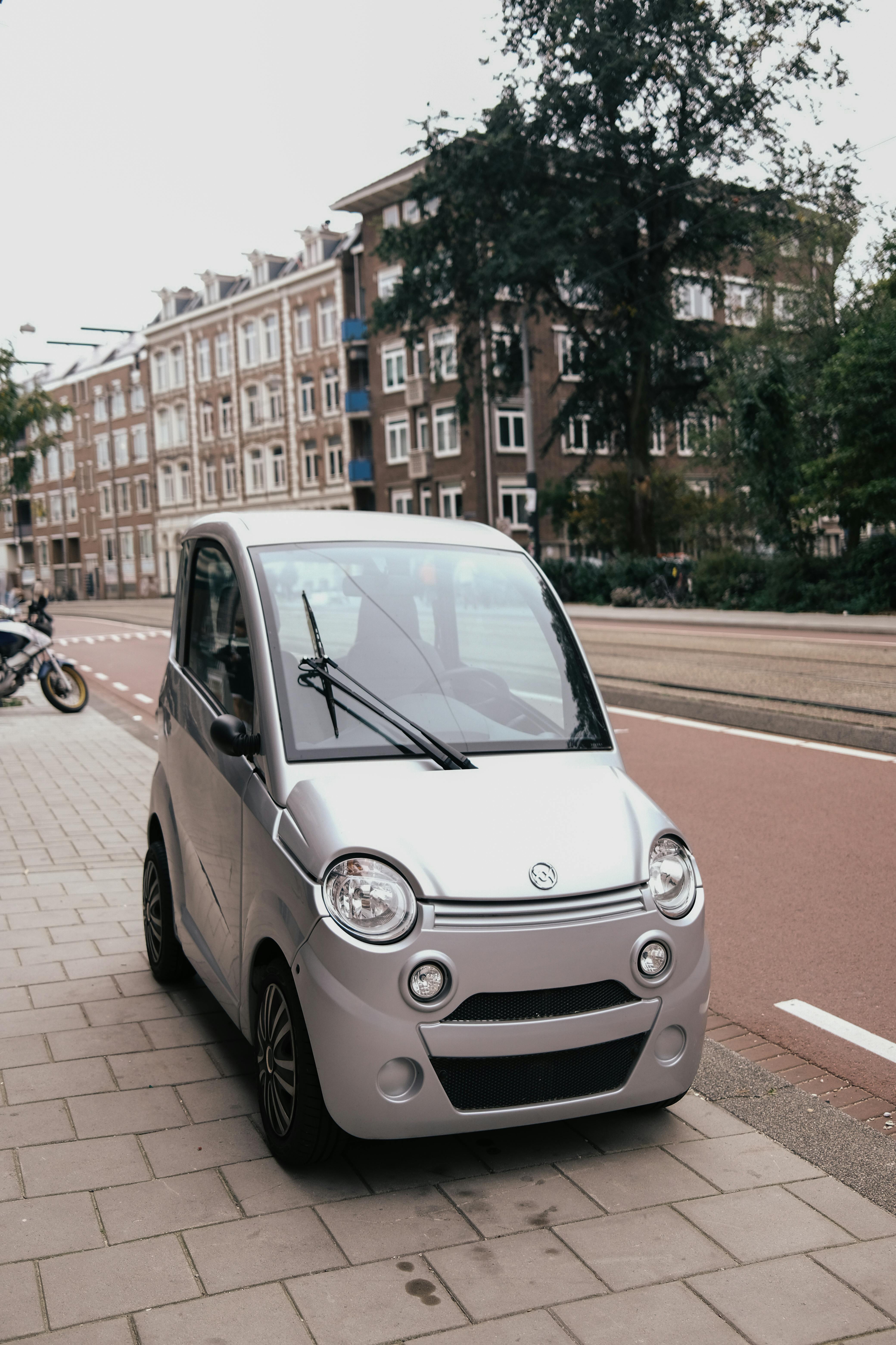 Компактный городской автомобиль, припаркованный вдоль тротуара