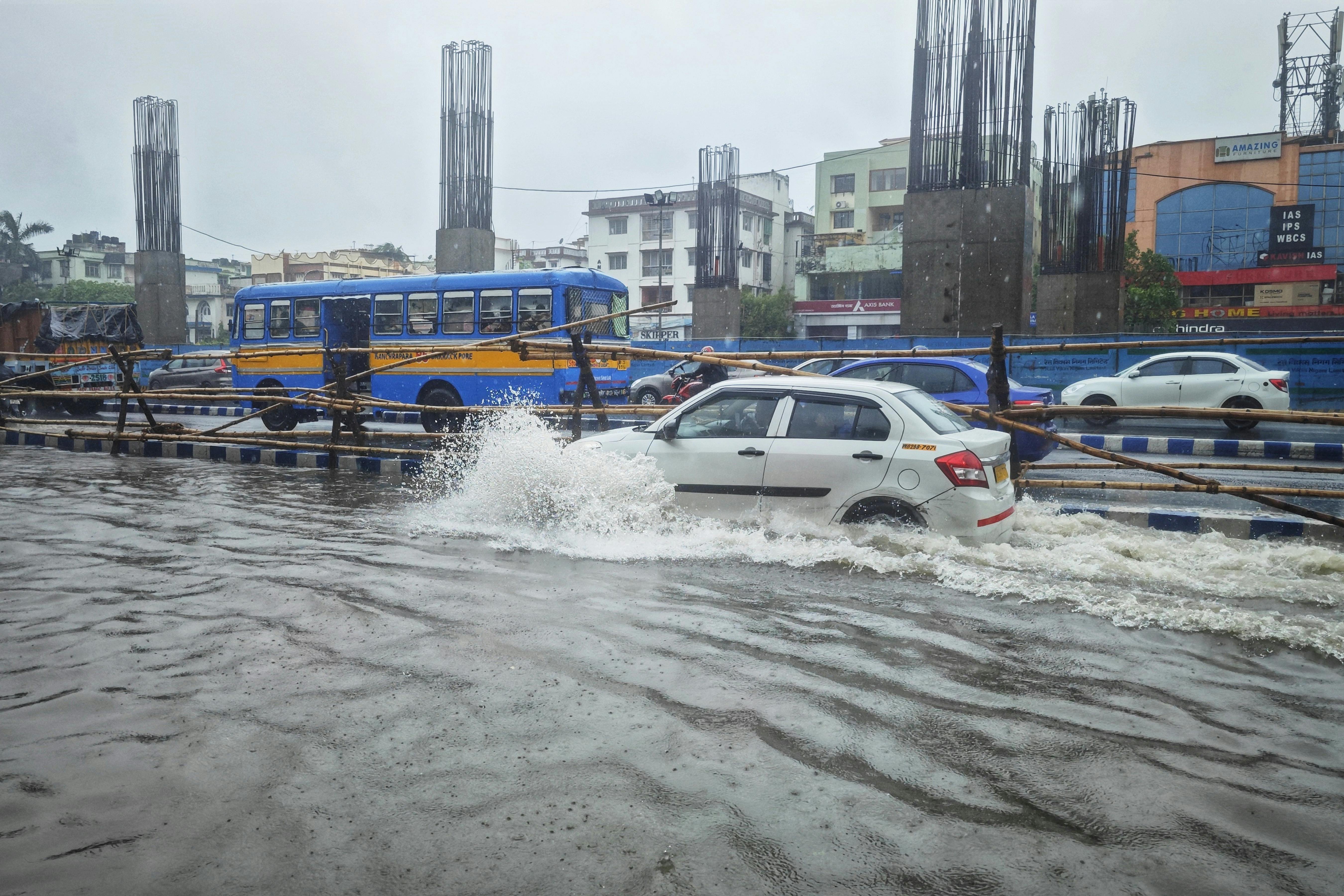 Mașini care se deplasează pe o stradă inundată în timpul unei ploi musonice