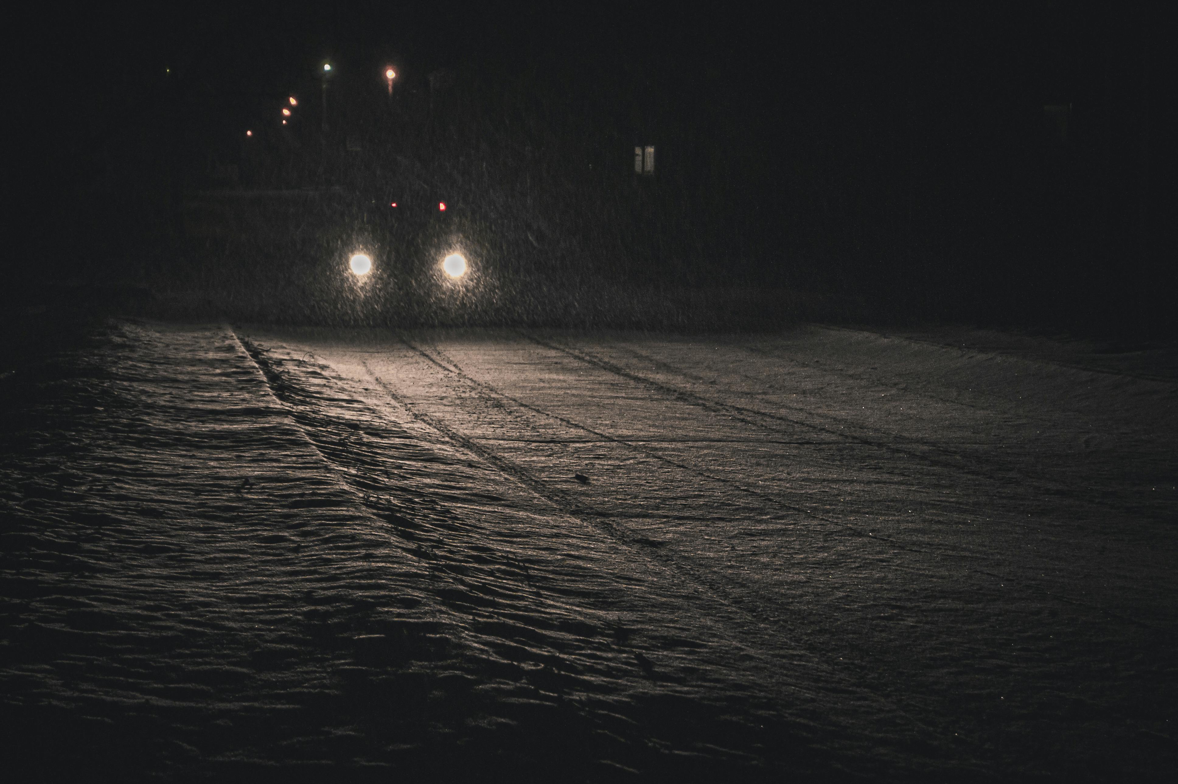Farurile mașinii pe un drum înzăpezit noaptea