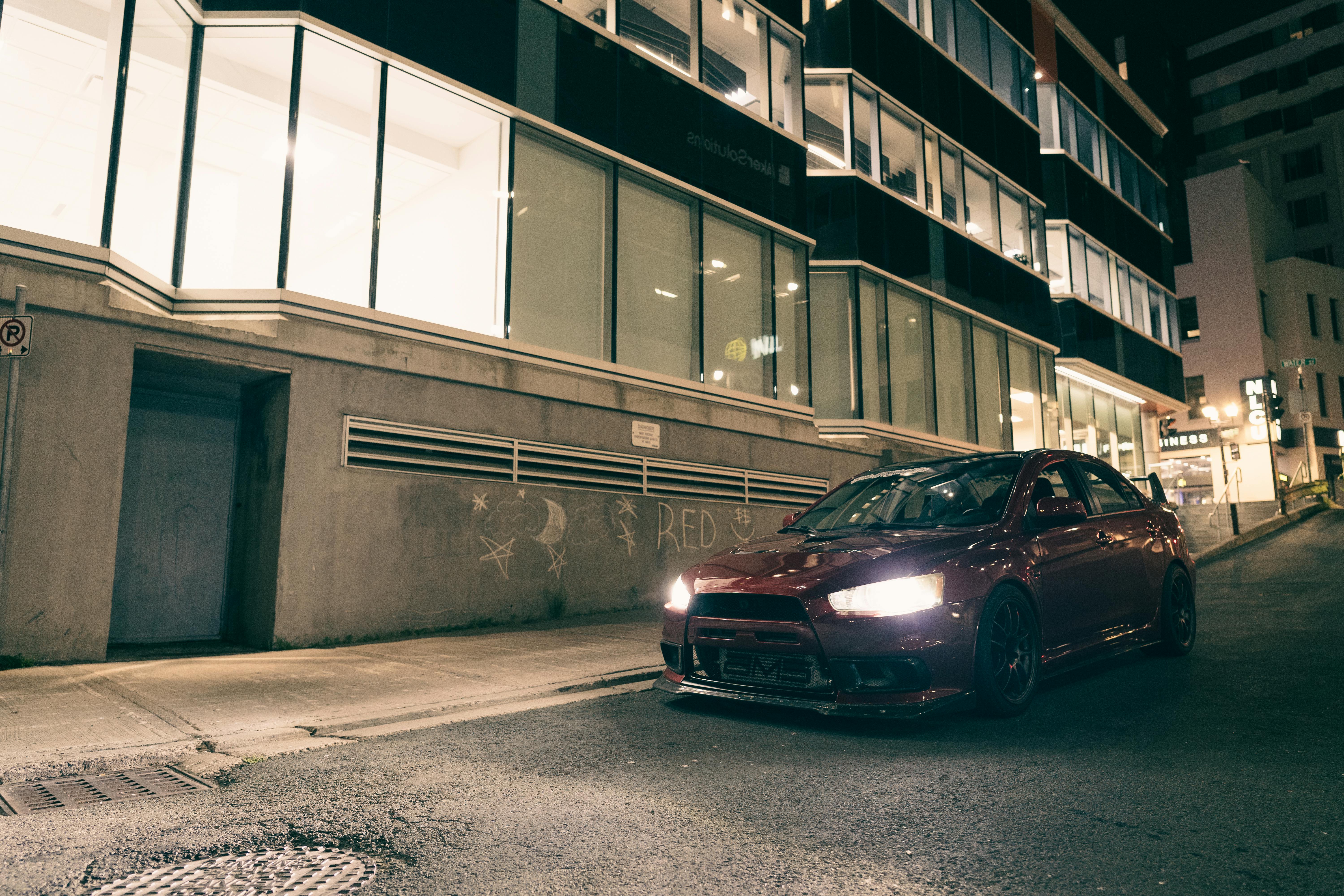 Стильний автомобіль, припаркований уночі на вулиці мегаполіса