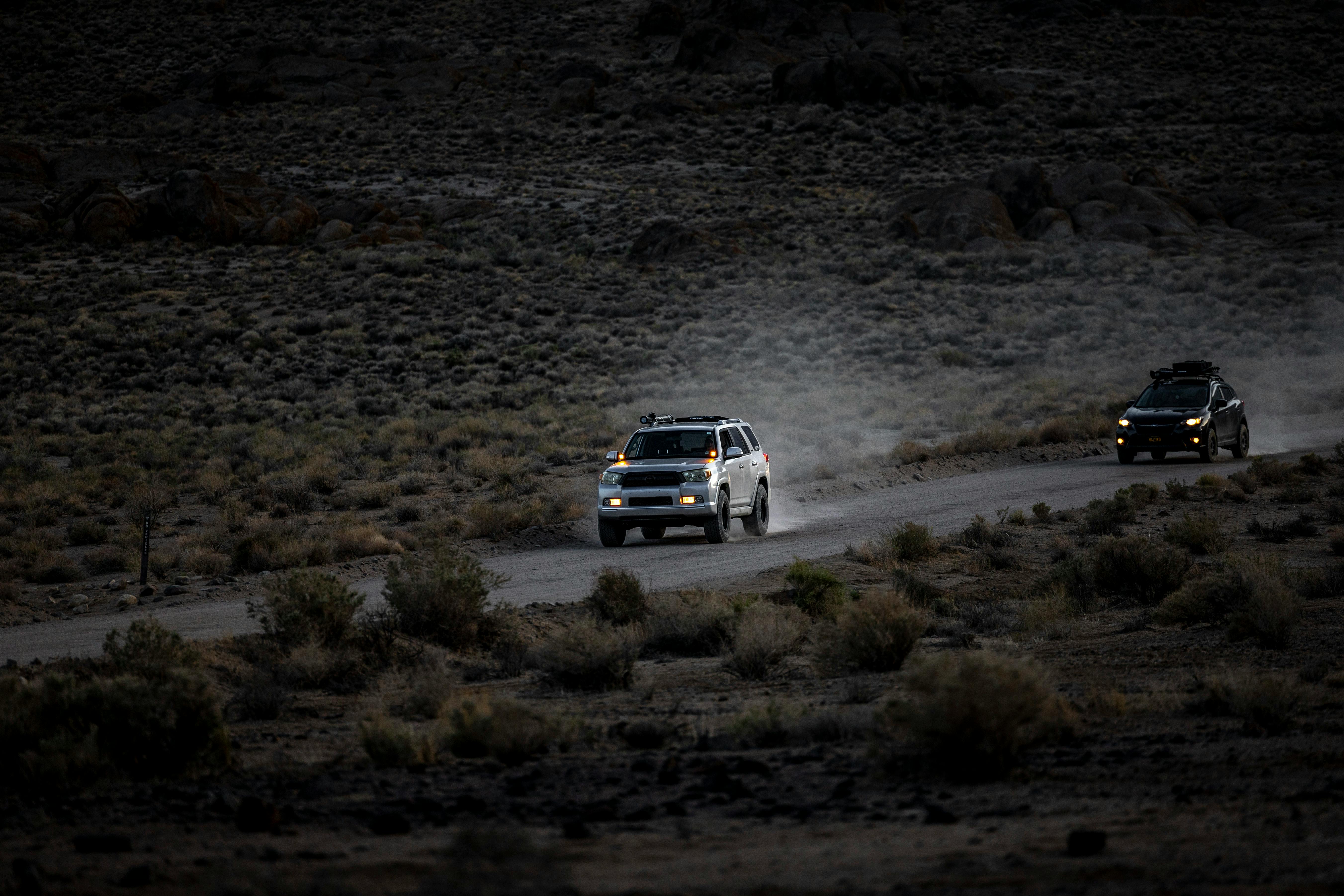 Білий позашляховик їде по гірській дорозі на заході сонця