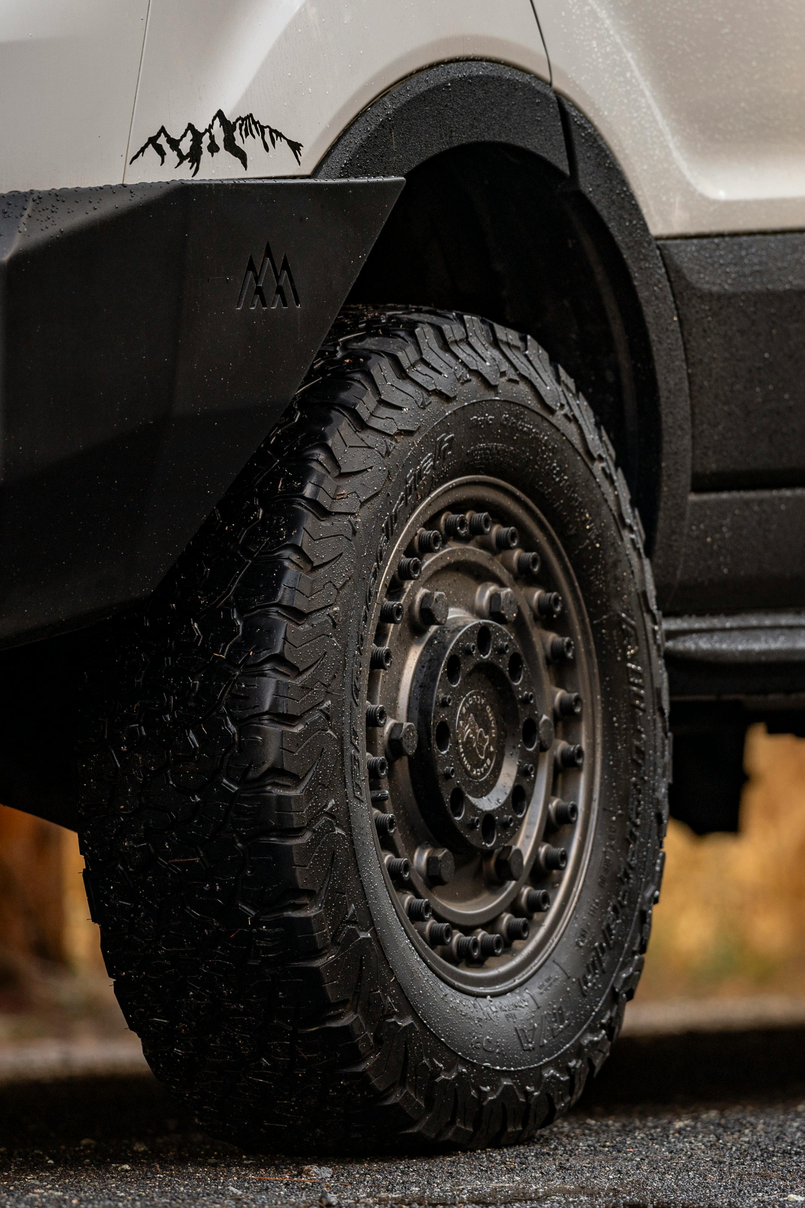 Prim-plan al benzii de rulare a unei anvelope all-terrain cu graffiti montan pe caroserie