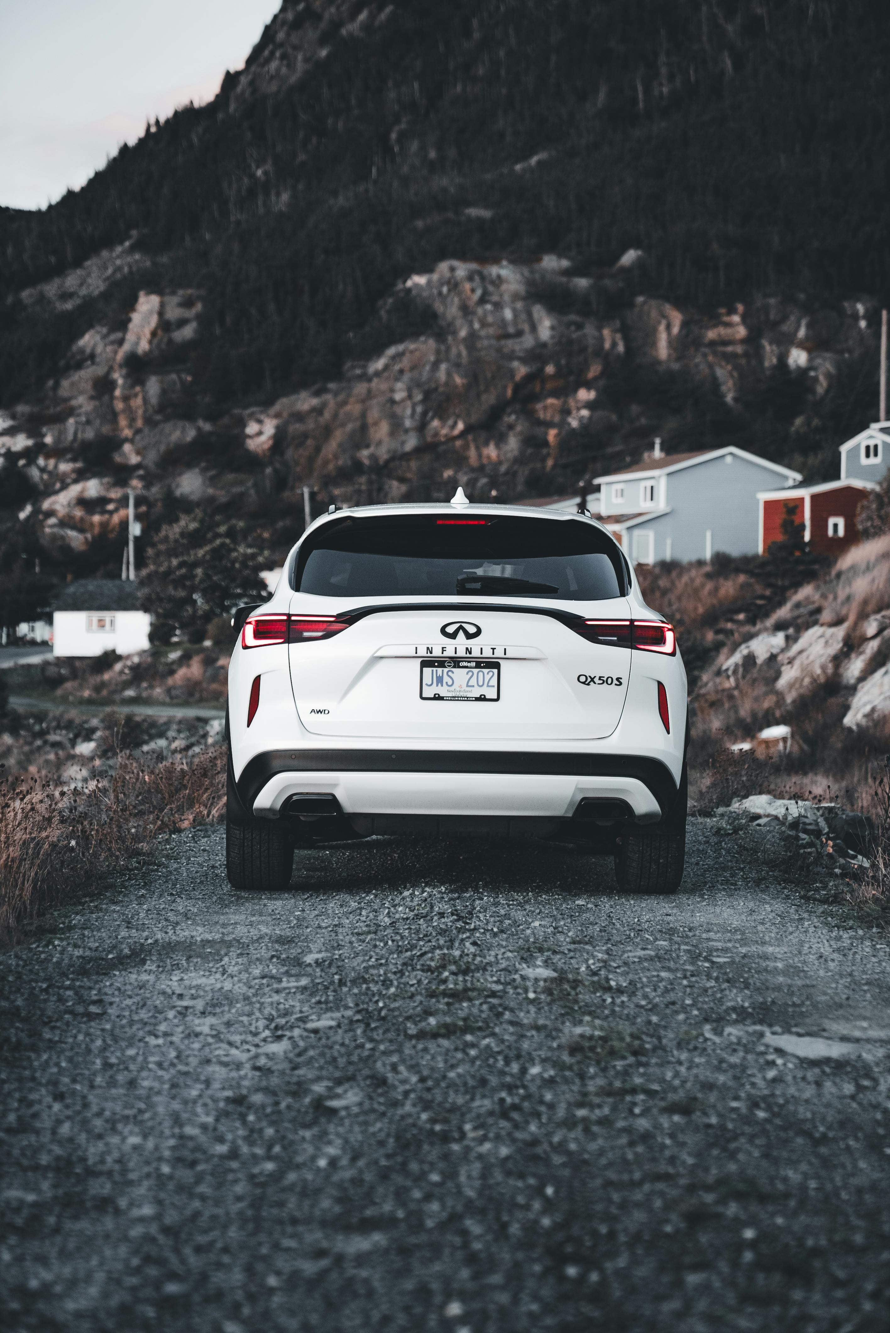 Crossover alb pe un drum de pietriș cu peisaj montan