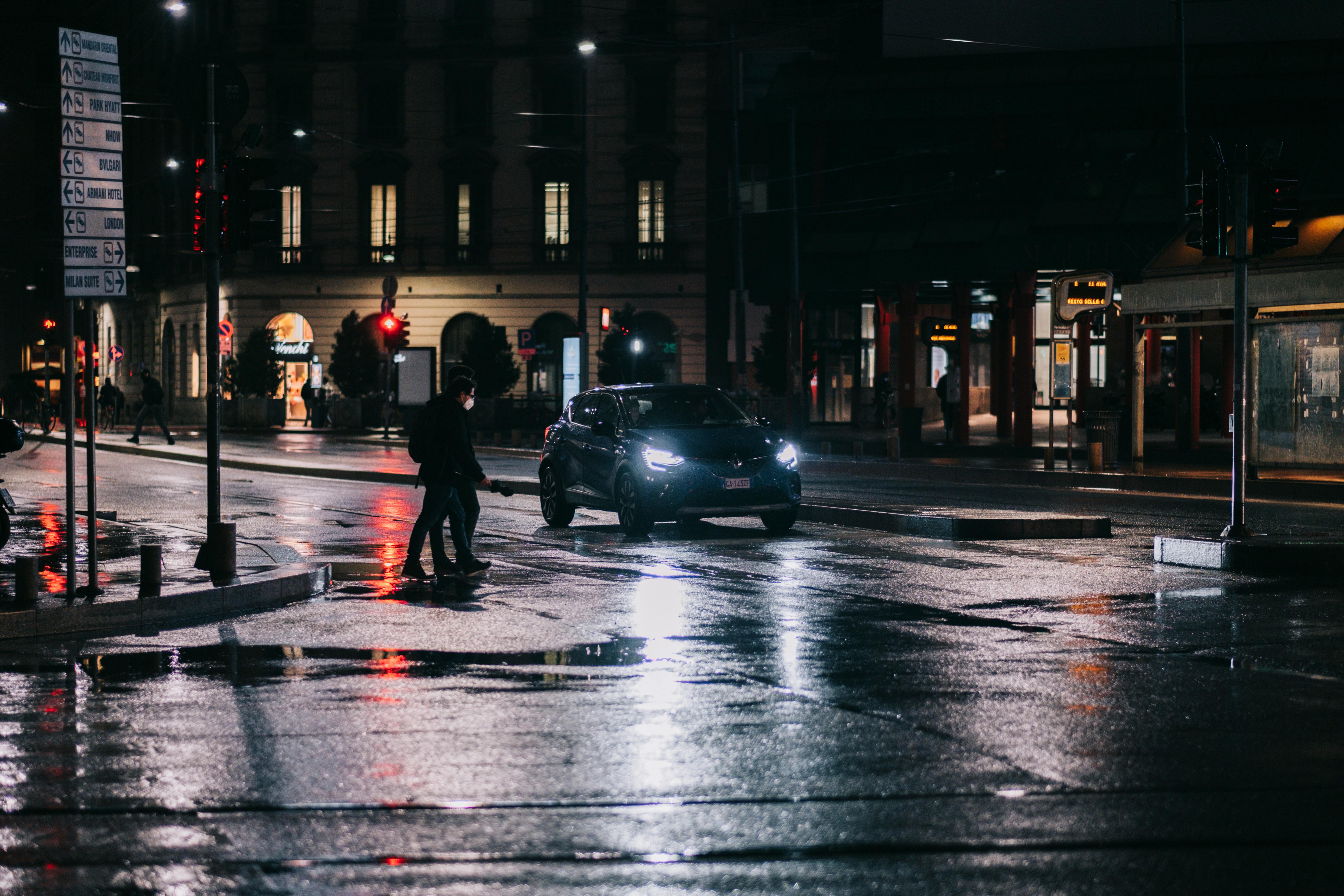 Пішоходи переходять дорогу перед автомобілем у вечірньому місті